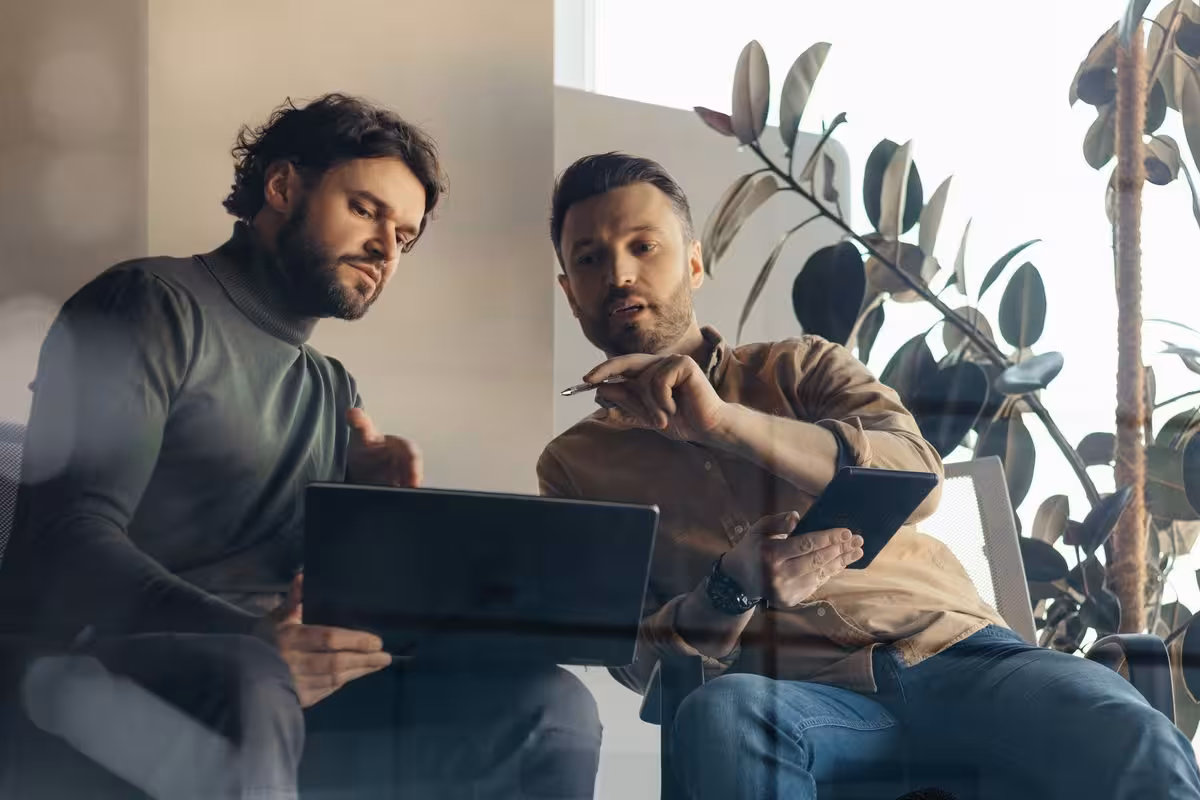 Two people going over a website together on a laptop and a tablet